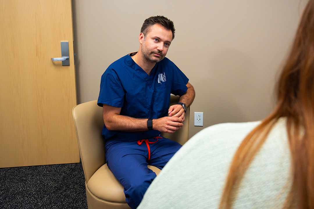 Dr. Luke Macyszyn listening to patient