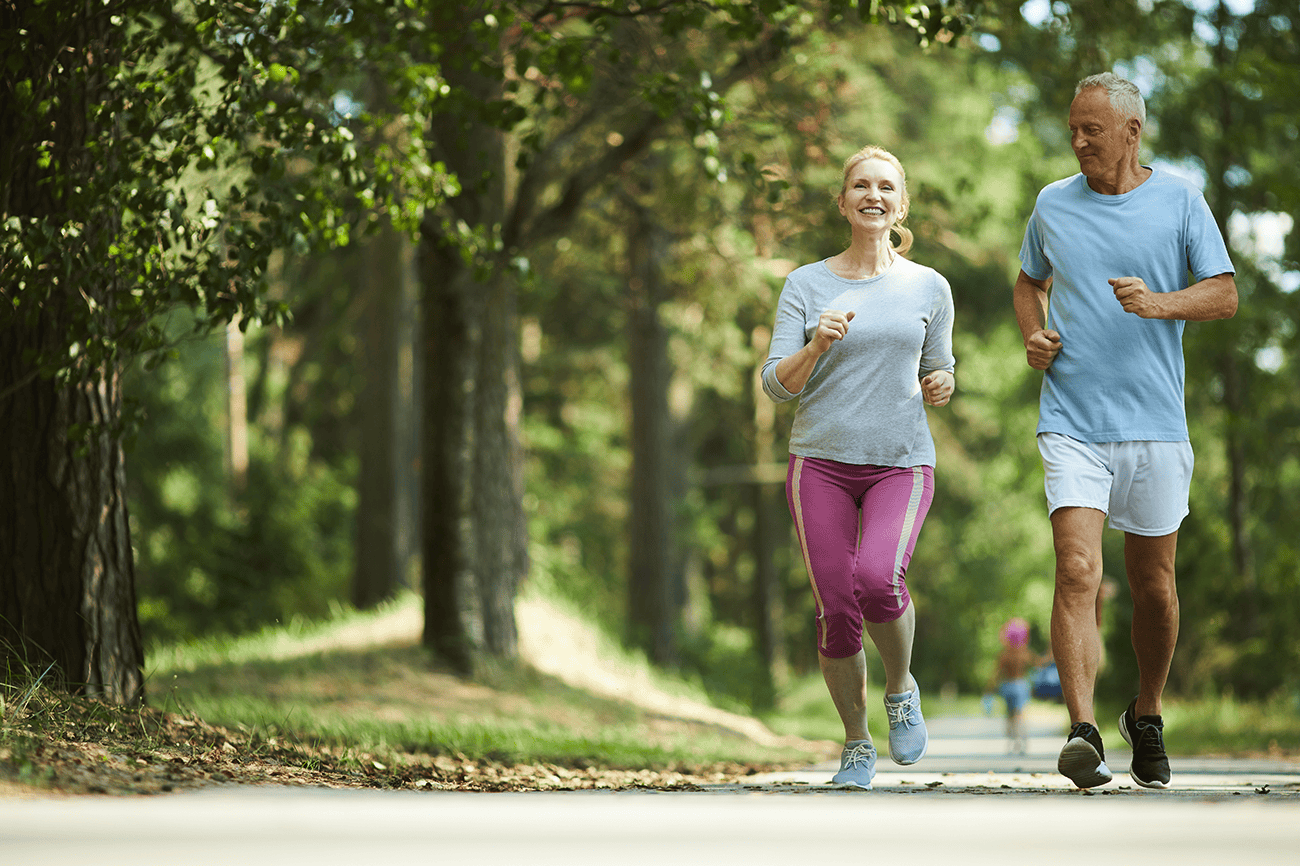 Middle aged couple running in forest